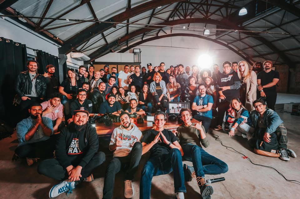 Large group photo of people gathered together inside a warehouse or studio