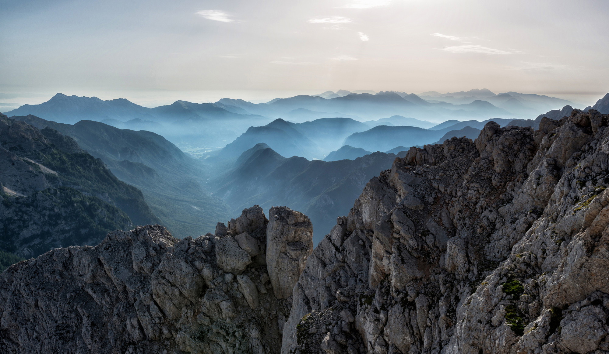 A small chapel at sunrise surrounded by mountains.